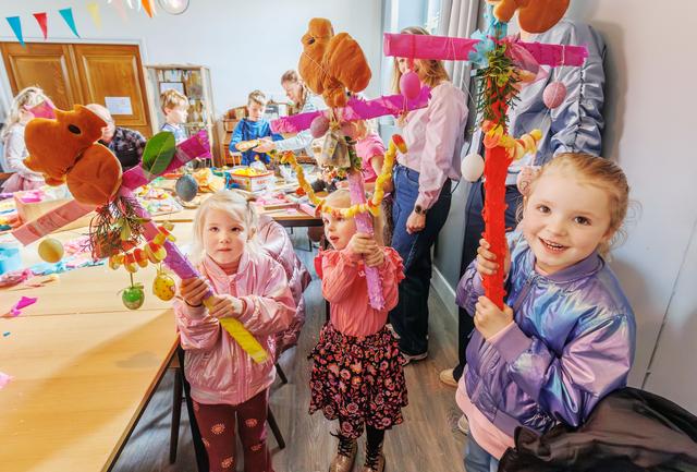 Kinderen versieren palmpasenstokken in volle kerk