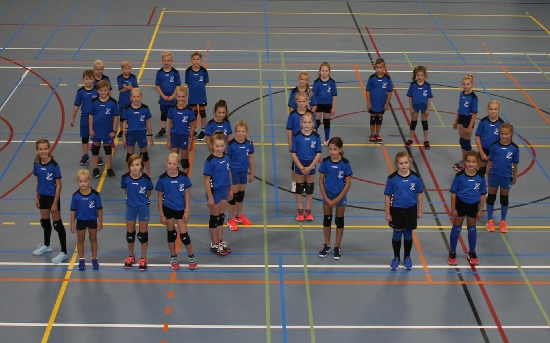 De nieuwe shirts worden uitgereikt aan de jongste volleyballers, die daarmee het getal 50 op de vloer vormen.