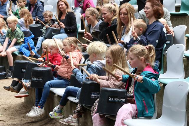 Kinderen trommelen er samen met de Vuilnismannen vrolijk op los in openluchttheater De Koele in Appe