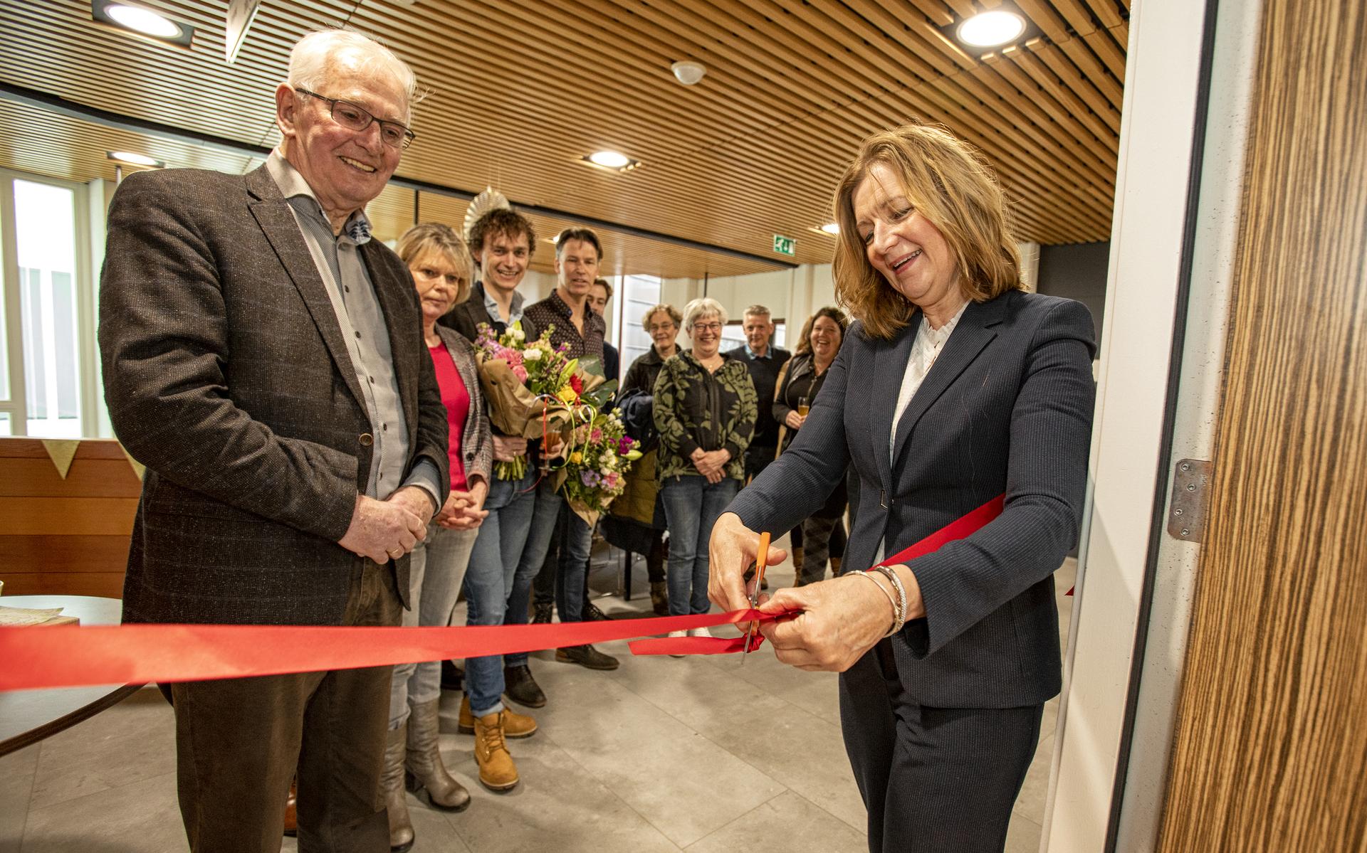 Met het doorknippen van een lint opent wethouder Esther Verhagen de nieuwe anderhalvelijnszorg in het Gezondheidscentrum. Bert Brouwer (links) en de overige aanwezigen kijken toe.