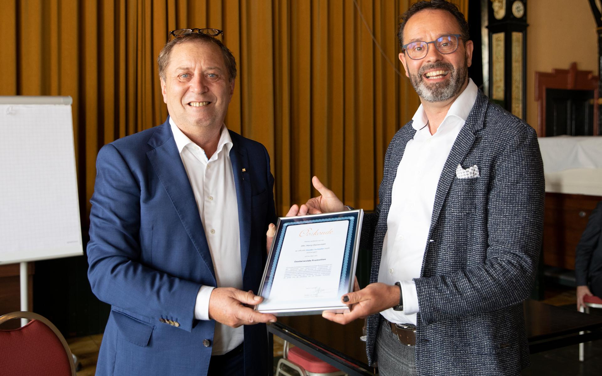 Uit handen van Henkjan van Zanten ontvangt vertrekkend burgemeester Harry Oosterman de Gouden Turfsteker en het bijbehorende certificaat.