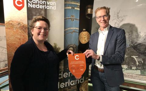 Gedeputeerde Nelleke Vedelaar (links) en directeur Friso Visser van museum De Proefkolonie tonen het Canonbordje.