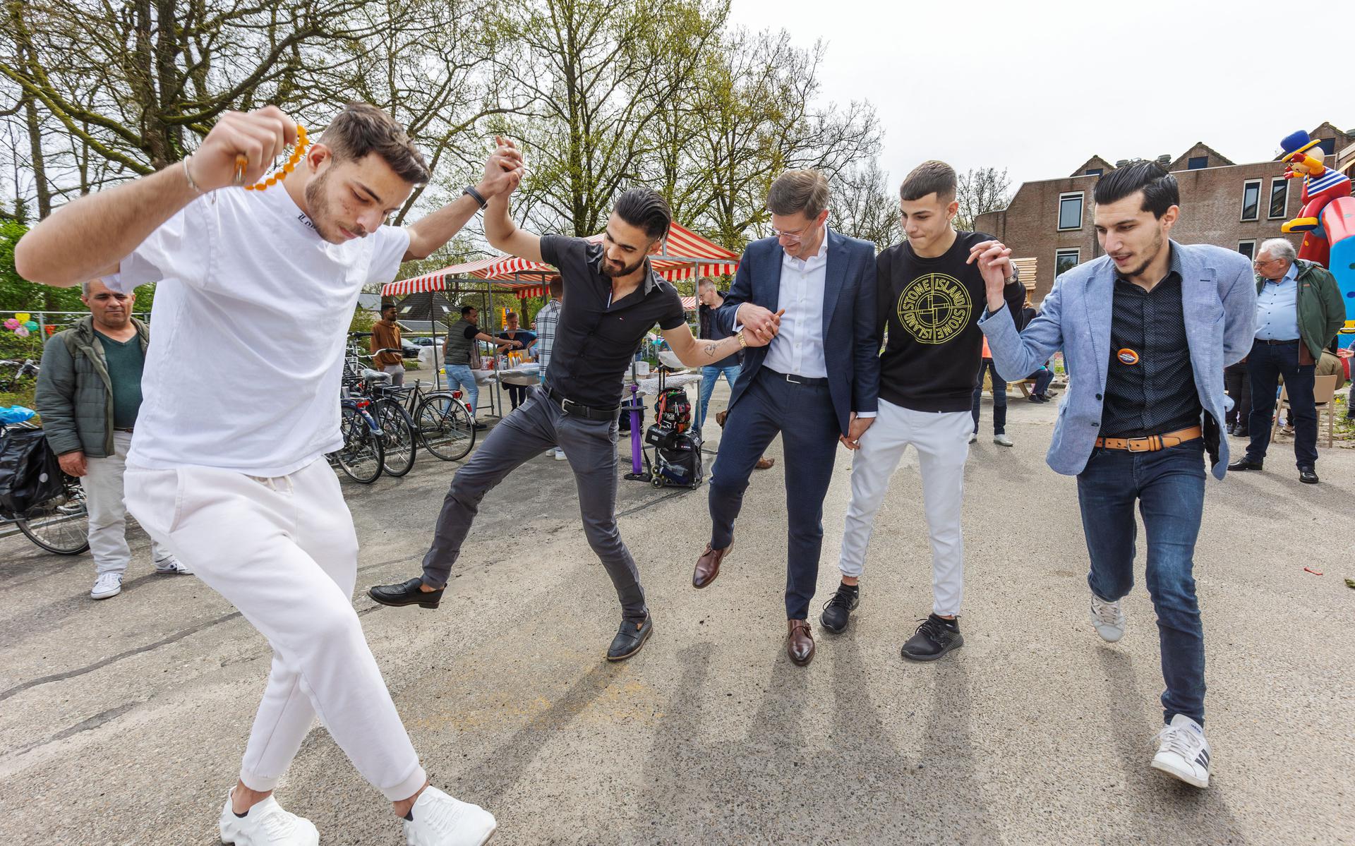 Statushouders die wonen in Rikkingahof dansen met burgemeester Jack Werkman (midden).